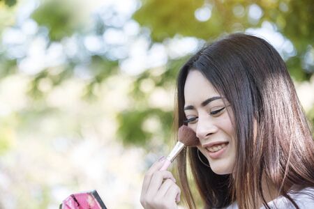 Glamour woman Makeup brush on with beauty brunette focus on happy face of young charming woman. Brush on cheek and smiling with happiness.の写真素材