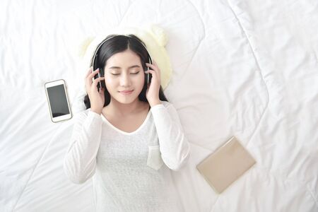 Leisure cheerful wellness woman Concept. Happy teenage woman listening to music wear headphones from smartphone outdoor in the park. Music mental therapist for wellness woman.の写真素材