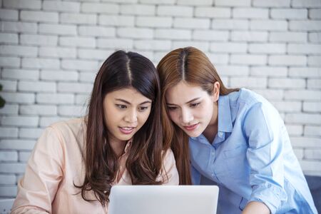Happy entrepreneur asian businesswomen using smartphone dealing negotiate for startup business. Two partners enjoy good news from smartphone teamwork collaboration asian woman working togetherの写真素材