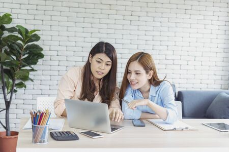 Happy entrepreneur asian businesswomen using smartphone dealing negotiate for startup business. Two partners enjoy good news from smartphone teamwork collaboration asian woman working togetherの写真素材