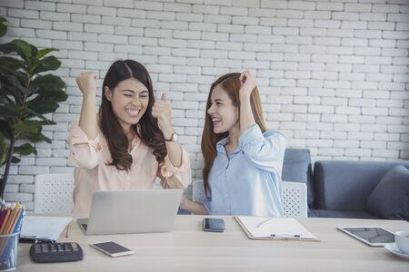 Happy entrepreneur asian businesswomen using smartphone dealing negotiate for startup business. Two partners enjoy good news from smartphone teamwork collaboration asian woman working togetherの写真素材