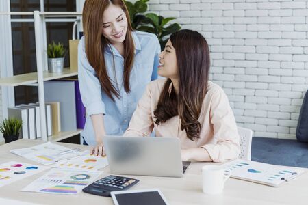 Happy entrepreneur asian businesswomen using smartphone dealing negotiate for startup business. Two partners enjoy good news from smartphone teamwork collaboration asian woman working togetherの写真素材