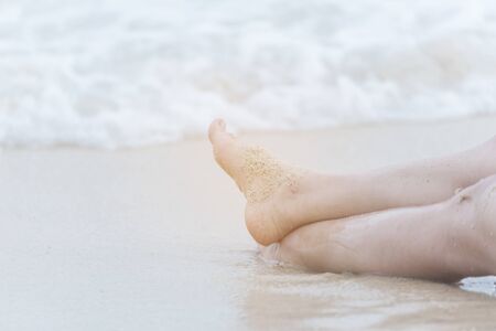 Woman bare foot walking on the summer beach. close up leg of young woman walking along wave of sea water and sand on the beach. Enjoyment barefoot walk outdoor with freedom. Relaxation Travel Concept.の写真素材