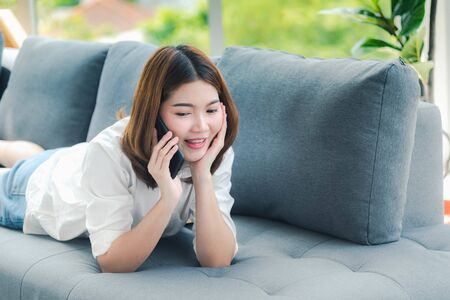 on smartphone. Smiling face of asian woman holding cellphone with E-commerce Shopping online website Reading Online Article, Blog and vlog.の写真素材