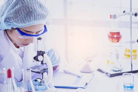 Female scientist look at microscope, science test tube analyse scientific sample in laboratory research experiment biotech make cultivate vaccine against virus. Chemistry science laboratory conceptの写真素材
