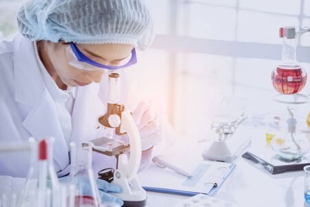 Female scientist look at microscope, science test tube analyse scientific sample in laboratory research experiment biotech make cultivate vaccine against virus. Chemistry science laboratory conceptの写真素材