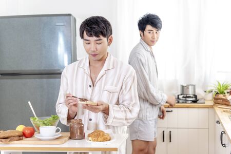 Asian gay couple homosexual cooking together in the kitchen prepare fresh vegetable make organic salad healthy food. Asian people happy time smile, laugh in kitchen. LGBTQ relation lifestyle conceptの写真素材