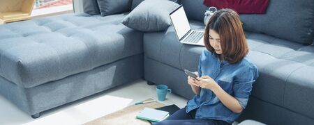 Banner asian woman using smartphone reading online social media shopping online website on smartphone with smile face. Happiness asian woman holding cellphone checking mail read Blog vlog social mediaの写真素材