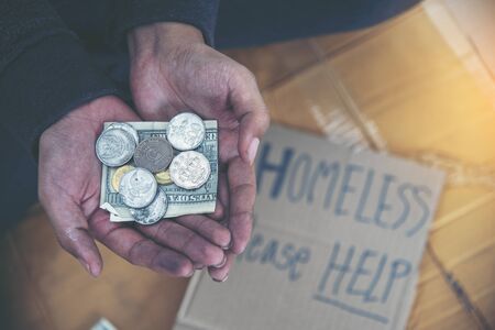 Homeless people poverty beggar man asking for money job and hoping help in helpless dirty city sitting with sign of cardboard box said "Homeless Please Help" on board. Beggar in city concept.の写真素材