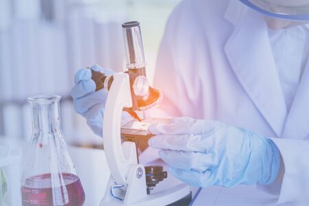 Female scientist look at microscope, science test tube analyse scientific sample in laboratory research experiment biotech make cultivate vaccine against virus. Chemistry science laboratory conceptの写真素材