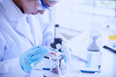 Female scientist look at microscope, science test tube analyse scientific sample in laboratory research experiment biotech make cultivate vaccine against virus. Chemistry science laboratory conceptの写真素材