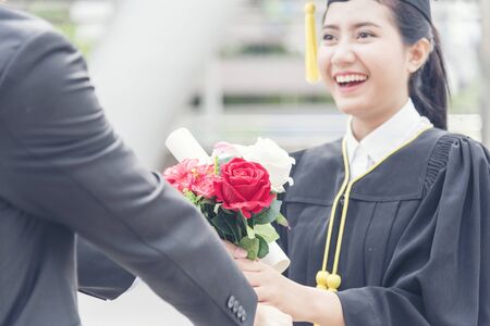 Graduated woman concept. Young smiling woman got flower after finish education. Graduate people finish academy university.の写真素材