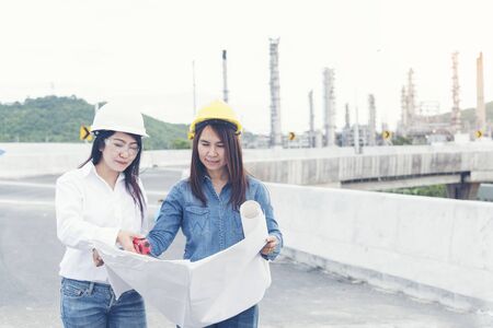 Smart woman engineer holding white hard hat on hand and look at refinery industry plant at industry factory center area. Engineering Conceptの写真素材