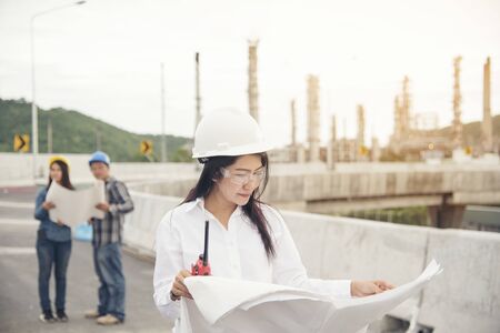 Smart woman engineer holding white hard hat on hand and look at refinery industry plant at industry factory center area. Engineering Conceptの写真素材