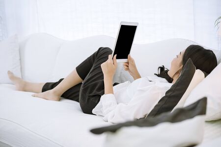Asian woman using phone shopping online website on smart tablet hand point touch screen digital...