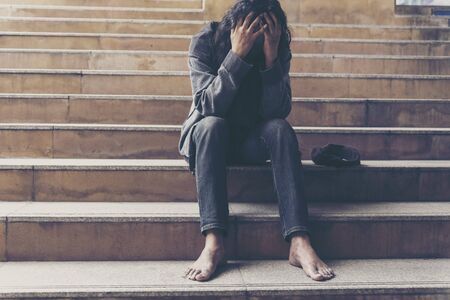 Homeless people poverty beggar man holding hands asking for money job and hoping help in helpless dirty city sitting on streets. Desperate Beggar in city concept.の写真素材