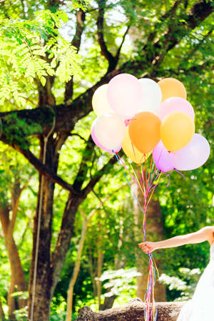 Young beautiful woman holding colorful air balloons in the park.  Relaxation on international women 's dayの写真素材