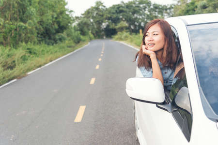 Young smiling woman getting keys of a new car. Concept for car rental. Enjoying road trip. Travel...