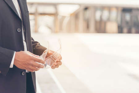 Businessman holding safety glasses in hands at construction site in the city. Construction Concept.の写真素材