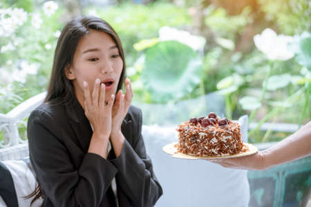 Happy woman eat cake delicious sweet dessert in chocolate cafe. Sweet fancy cake got a surprise birthday gift sugar tasty plate in coffee shop. Woman sitting on cozy sofa holding sweet cupcakeの写真素材