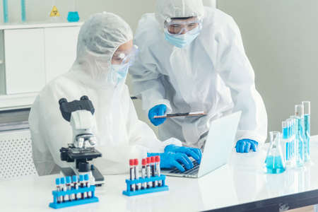 Scientist covid-19 virus antibody research laboratory research experiment biotech cultivate vaccine against virus. Scientist look at microscope experiment lab science test tube Chemistry laboratoryの写真素材