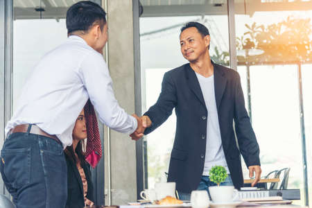 Team Business Partners shaking hands together to Greeting Start up small business in meeting room. Shakehand teamwork partners at modern office handshake together. Business mergers and acquisitionsの写真素材