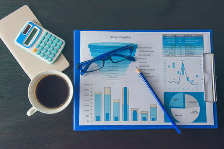 Office laptop business financial document chart and graph on wooden table with coffee cup. Flat lay notebook computer laptop on office desk. No people business graph chart mockup on business workspaceの写真素材