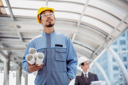 Construction engineer in Safety Suit Trust Team Holding White Yellow Safety hard hat Security Equipment on Construction Site. Hardhat Protect Head for Civil Construction Engineer. Engineering Conceptの写真素材