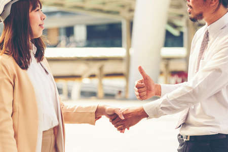 Civil Construction engineer teams shaking hands together wear work helmets worker on construction site. Foreman industry project working engineer teamwork. Two asian engineer team shake hands togetherの写真素材