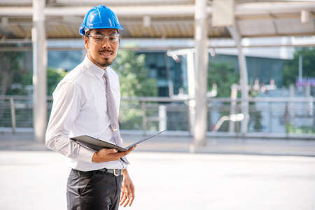 Construction engineer in Safety Suit Trust Team Holding White Yellow Safety hard hat Security Equipment on Construction Site. Hardhat Protect Head for Civil Construction Engineer. Engineering Conceptの写真素材