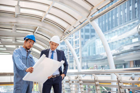 Construction engineer in Safety Suit Trust Team Holding White Yellow Safety hard hat Security Equipment on Construction Site. Hardhat Protect Head for Civil Construction Engineer. Engineering Conceptの写真素材