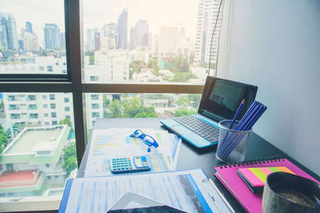 Office laptop business financial document chart and graph on wooden table with coffee cup. Flat lay notebook computer laptop on office desk. No people business graph chart mockup on business workspaceの写真素材