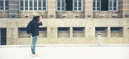 Banner Asian tourist using dslr professional camera travel on vacation. Female young traveler with backpack and photo camera in old town with copy space. Panoramic Beautiful woman traveller backpackの写真素材