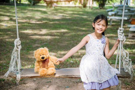 Happy Child hug teddy bear in green park playground. Teddy bear best friend for little kids cute girl. Autism happy funny playing together on playground in happiness family feel love and warm hugsの写真素材