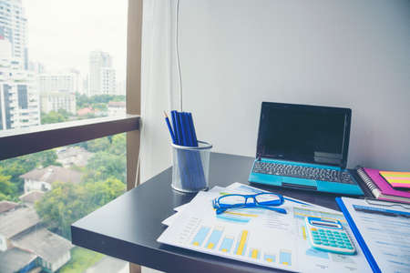 Office laptop business financial document chart and graph on wooden table with coffee cup. Flat lay notebook computer laptop on office desk. No people business graph chart mockup on business workspaceの写真素材