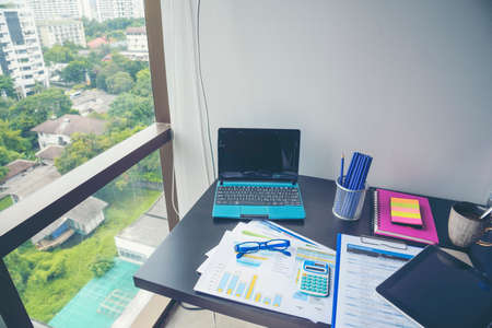 Office laptop business financial document chart and graph on wooden table with coffee cup. Flat lay notebook computer laptop on office desk. No people business graph chart mockup on business workspaceの写真素材