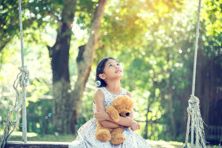 Happy Child hug teddy bear in green park playground. Teddy bear best friend for little kids cute girl. Autism happy funny playing together on playground in happiness family feel love and warm hugsの写真素材