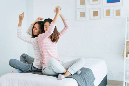 Two pretty best friends forever girlfriend talk, hug and laugh together on bed at cozy home relation fall in love. Lesbian couple homosexual happy lifestyle on bed. LGBTQ relation lifestyle concept.の写真素材