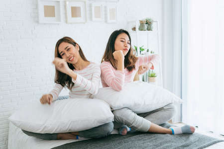 Two pretty best friends forever girlfriend talk, hug and laugh together on bed at cozy home relation fall in love. Lesbian couple homosexual happy lifestyle on bed. LGBTQ relation lifestyle concept.の写真素材