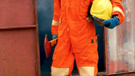 Firefighter fighting with flame using fire hose chemical water foam spray engine. Fireman wear hard hat, body safe suit uniform for protection. Rescue training in fire fighting extinguisherの写真素材