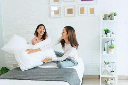 Two pretty best friends forever girlfriend talk, hug and laugh together on bed at cozy home relation fall in love. Lesbian couple homosexual happy lifestyle on bed. LGBTQ relation lifestyle concept.の写真素材