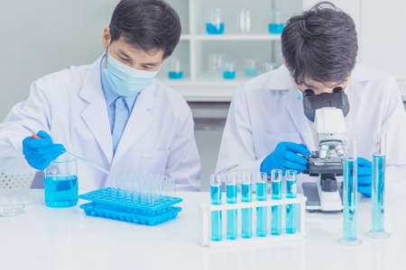 Two asian scientist team reserch chemistry science tube experiment biotech antibody sample in laboratory Cultivate Vaccine against covid-19 virus. Scientist consult, analyze in Chemistry Laboratoryの写真素材