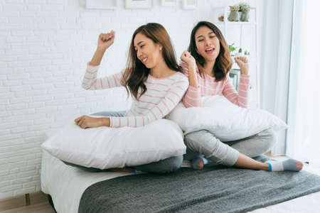 Two pretty best friends forever girlfriend talk, hug and laugh together on bed at cozy home relation fall in love. Lesbian couple homosexual happy lifestyle on bed. LGBTQ relation lifestyle concept.の写真素材