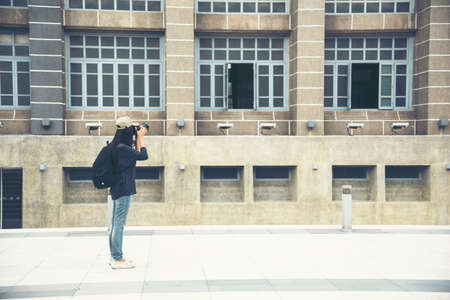 Asian tourist using dslr professional camera travel on vacation. Female young traveler with backpack and photo camera in the old town. Beautiful woman backpack around the word. Young traveller conceptの写真素材