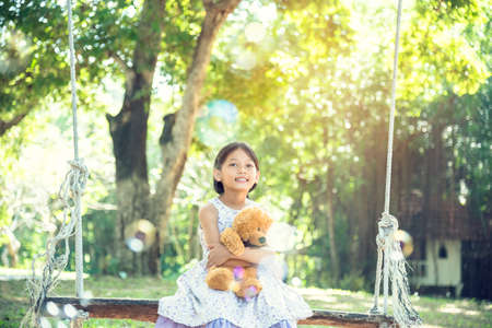 Happy Child hug teddy bear in green park playground. Teddy bear best friend for little kids cute girl. Autism happy funny playing together on playground in happiness family feel love and warm hugsの写真素材