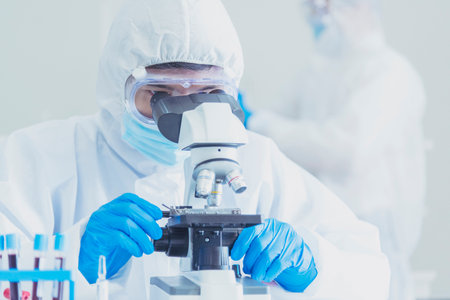 Male Scientist look into Microscope research in science laboratory. Asian scientist looking equipment laboratory chemistry labs. Covid-19 coronavirus biochemistry research experiment vaccine conceptの写真素材