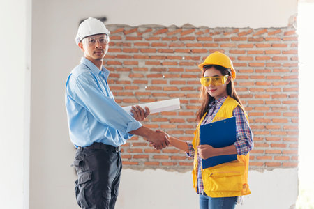 Civil Construction engineer teams shaking hands together wear work helmets worker on construction site. Foreman industry project working engineer teamwork. Two asian engineer team shake hands togetherの写真素材