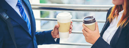 Banner Businessman Businesswoman drink coffee in town outside office modern city. Panoramic Hands holding take away coffee cup talking together happy. Copy Space Partner Business people cup of coffeeの写真素材