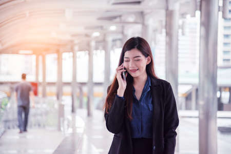 Business woman using smartphone shopping online, call, texting message internet technology lifestyle. Asian woman using cellphone walking on city street. Smart phone smart confident woman modern cityの写真素材