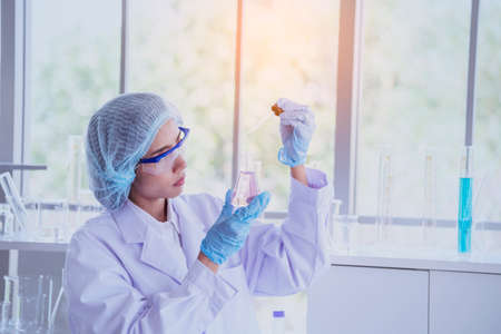 Female scientist look at microscope, science test tube analyse scientific sample in laboratory...